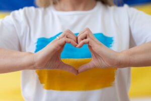 Mujer con camiseta con la bandera de Ucrania, formando un corazón con sus manos