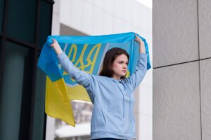 Joven ucraniana extendiendo con sus brazos a lo alto la bandera de Ucrania